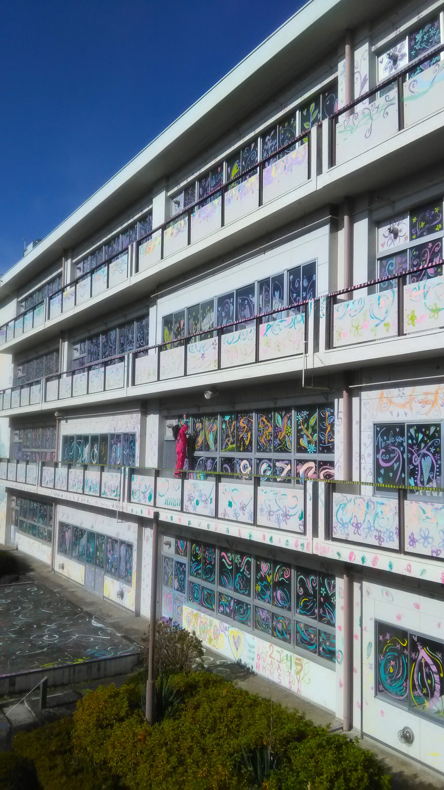 旧校舎取り壊し前の約1カ月間、卒業生が自由に彩色できるようにペンキを設置。「校舎に感謝の花束を」という想いを込めて、外壁や窓に色とりどりの花やハートなどが描かれた。（ワンダーアート提供）
