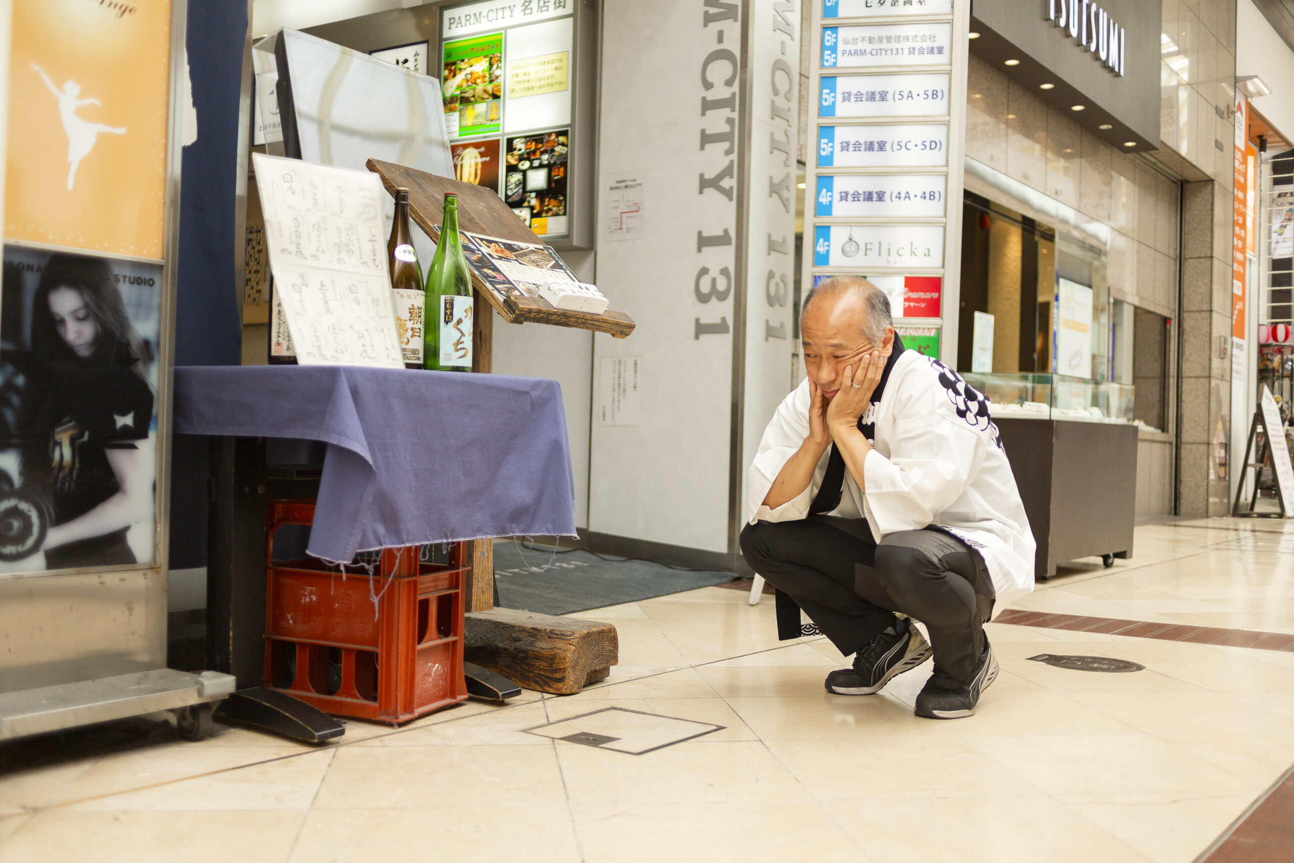 現在の「鳴海屋商事」があるビルの前は、自宅兼倉庫の入り口だった。いつもそこにゴザを敷き、おじいさんが座って針金鉄砲を作っていたという。特に会話はなかったが、鳴海さんは、この写真のように横でただ眺めているだけでワクワクしていたそう。