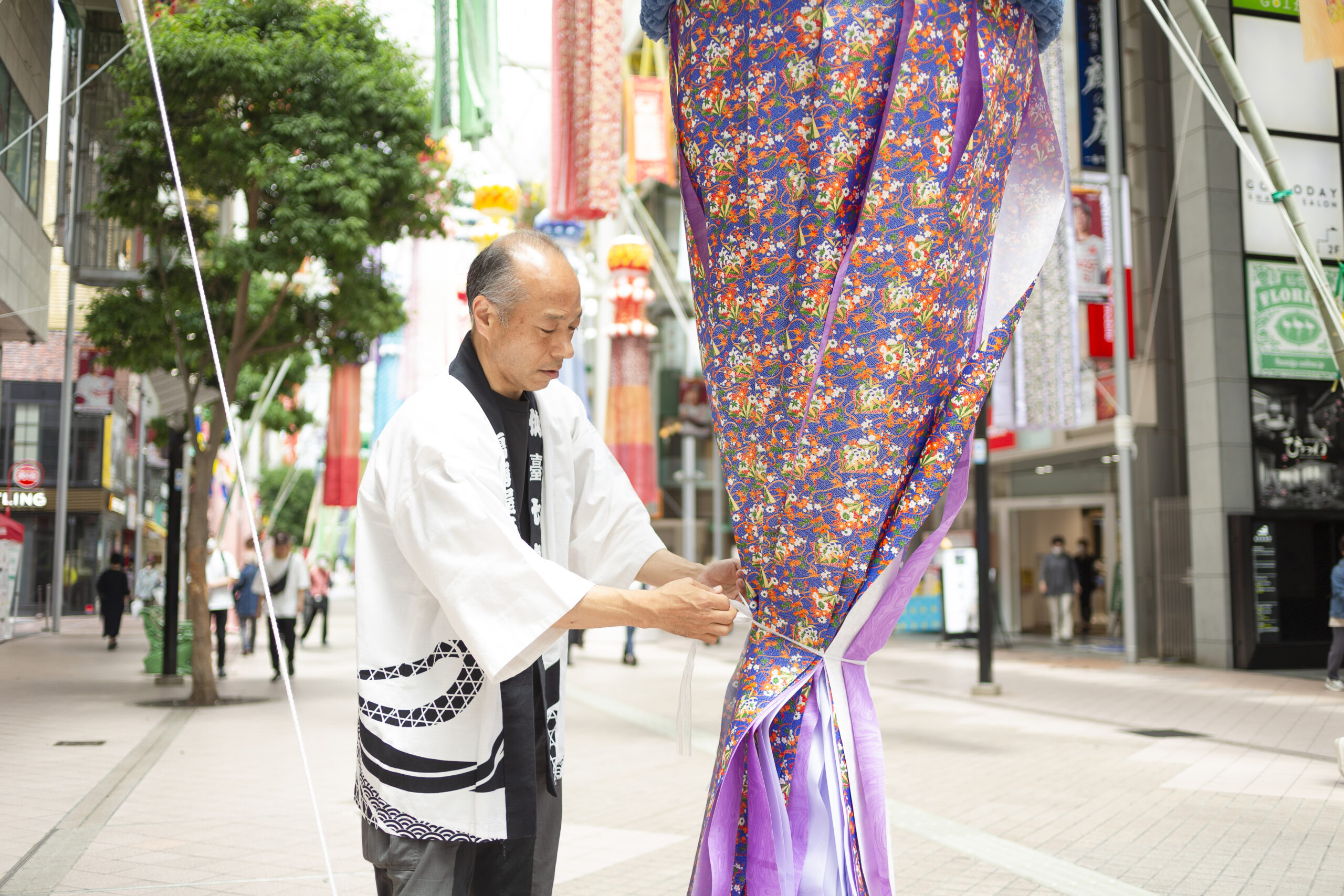 七夕まつりの期間中、鳴海さんは毎日朝9時までに七夕飾りを出し、21時以降に養生する。紐と器具を見事に扱い、掲出も養生もあっという間。