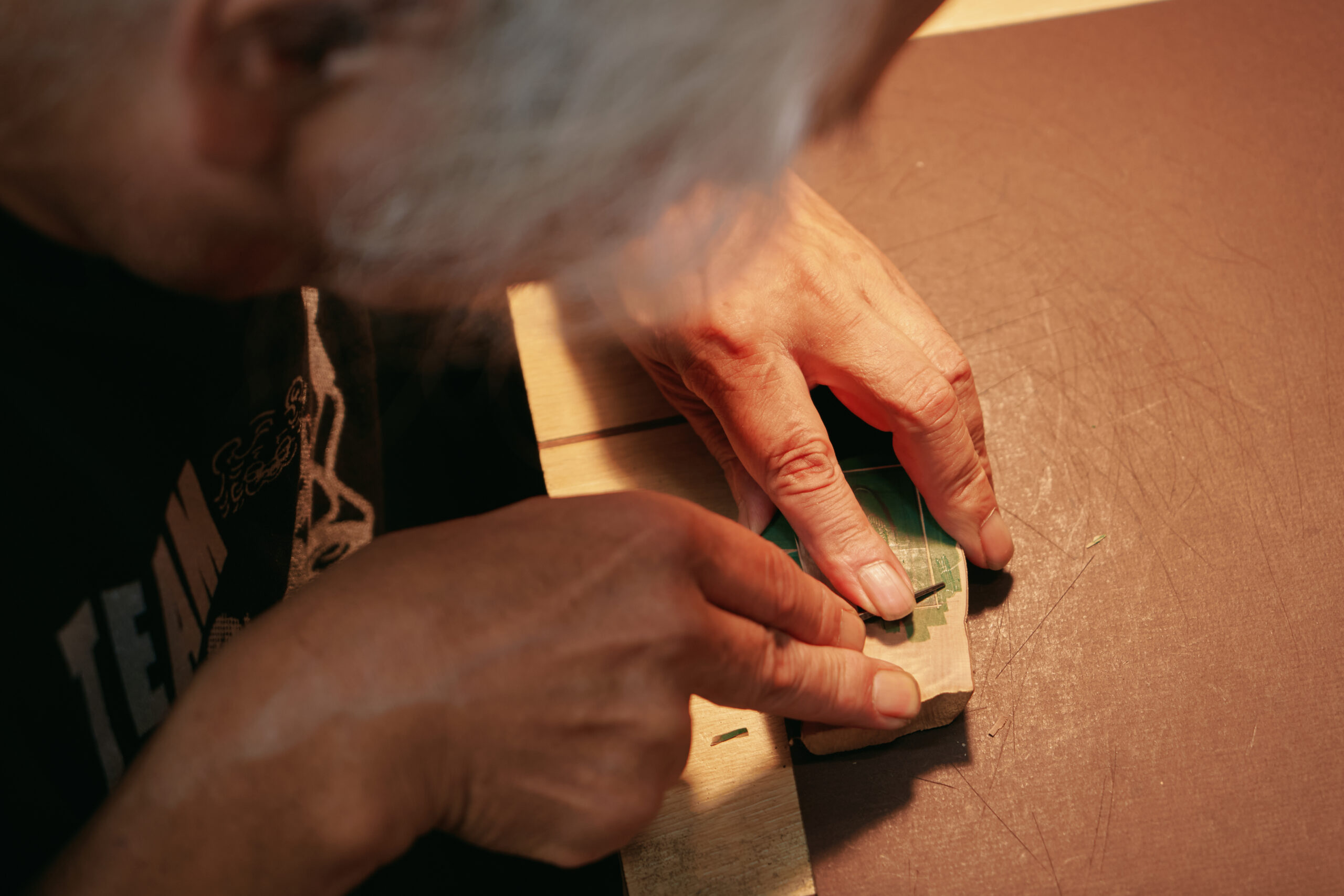 アトリエで創作に向き合う尾﨑さん。輪切りにした木材の表面を版木にし、ビュランを用いて繊細な表現をしていく。